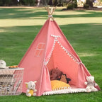 Tipi enfant intérieur rose avec pompons, créant un coin de jeu douillet et chic.