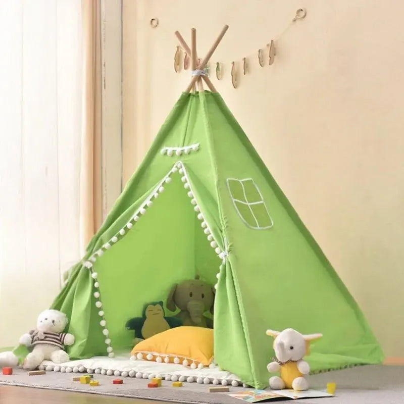 Tipi enfant intérieur vert avec pompons, créant un coin de jeu frais et douillet.